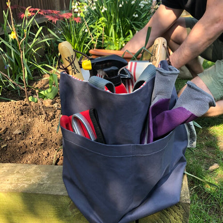 a grey blue bag in the garden containing garden tools